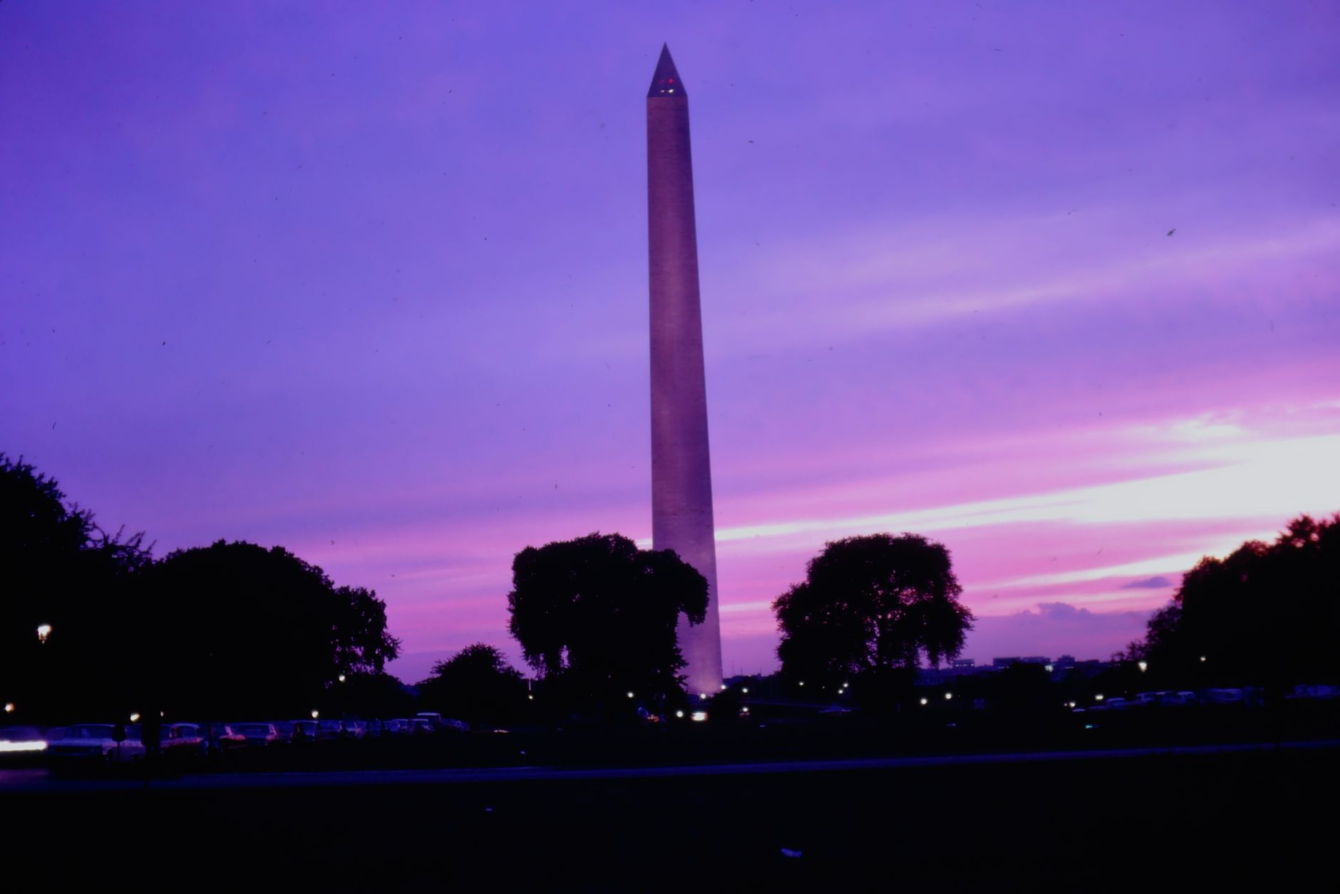Twilight view of the Washington Monument silhouetted against a vibrant purple and pink sky.