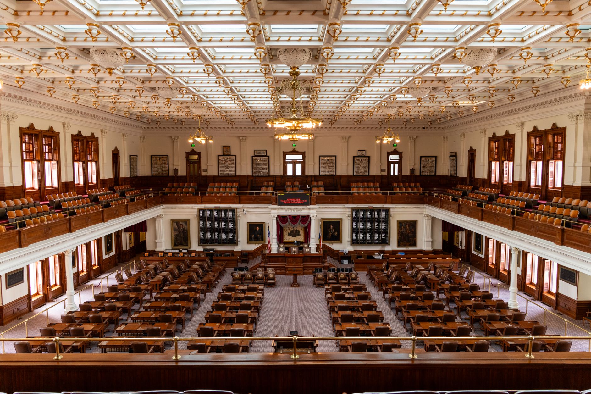 Spacious interior of the Texas State Capitol House Chamber with seating and elaborate ceiling.