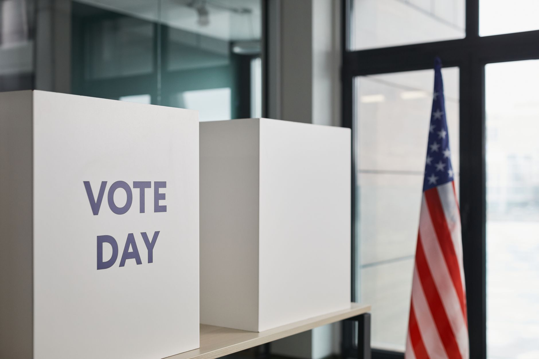 Voting booths marked Vote Day beside an American flag
