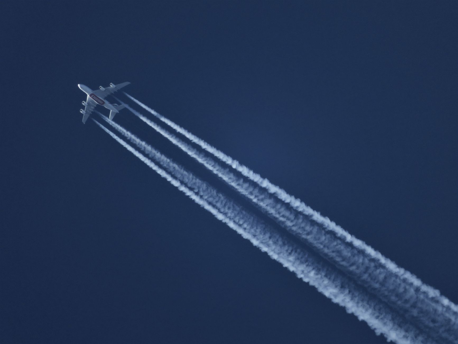 High-altitude airplane leaving contrails in a clear blue sky. Captured mid-flight.
