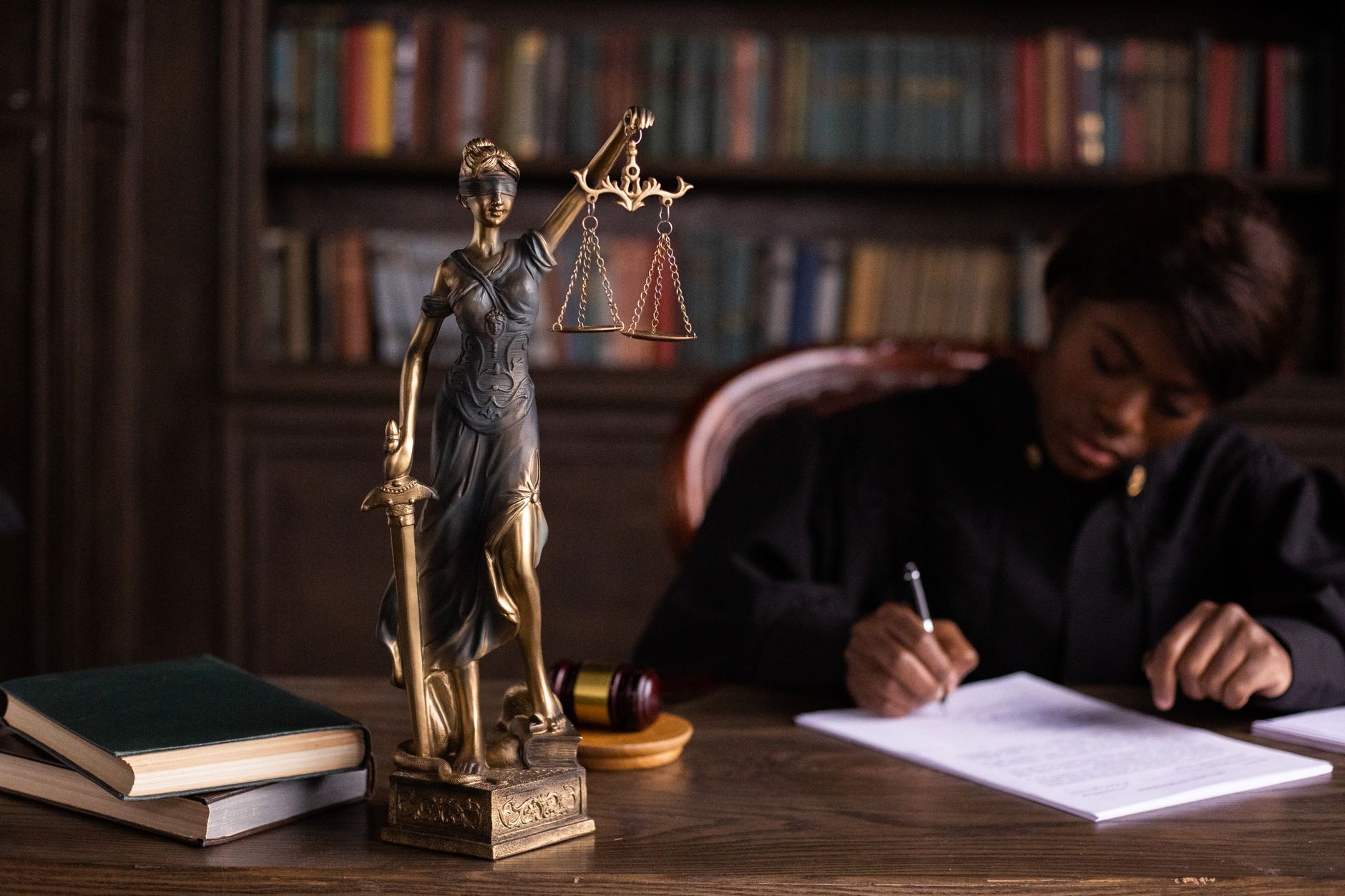 Statue of Lady Justice beside a person writing at a desk