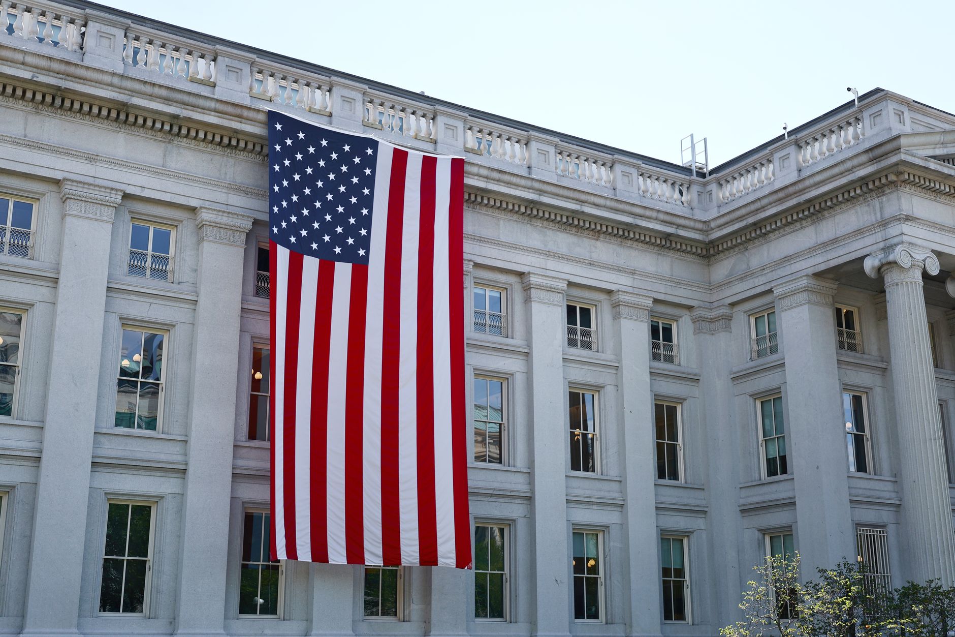 A large American flag hangs on a historic government building in Washington, D.C., showcasing national pride.
